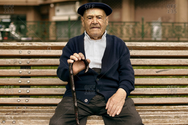 Bilbao, Spain - July 10, 2010. An old Basque man wears a traditional Basque beret and is sitting with his stick on a bench in Bilbao