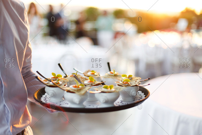 Server holding a platter of hors d\'oeuvres in small dishes