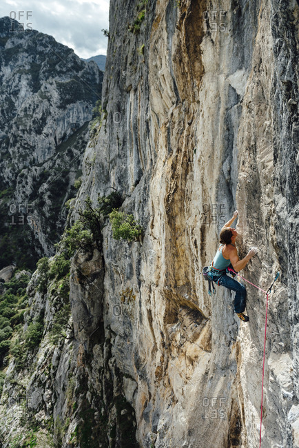 Young climber woman looking to clip her next draw in Asturias, Spain