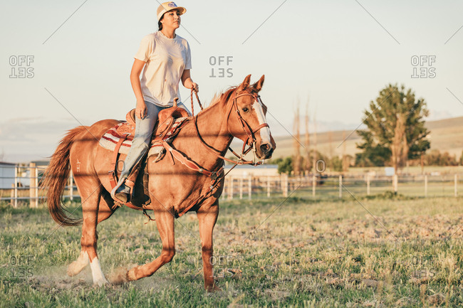 Umatilla Reservation, Pendleton, Oregon - May 18, 2017: Girl riding brown horse on the Umatilla Reservation in Oregon at sunset
