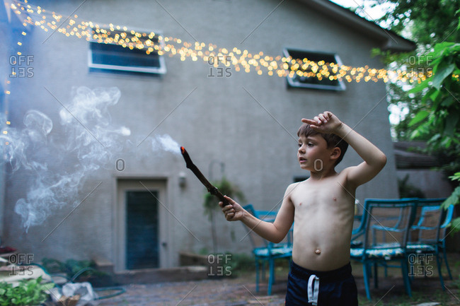 Boy with a burning stick on patio