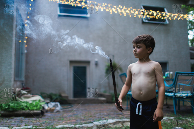 Boy with a smoking stick on patio