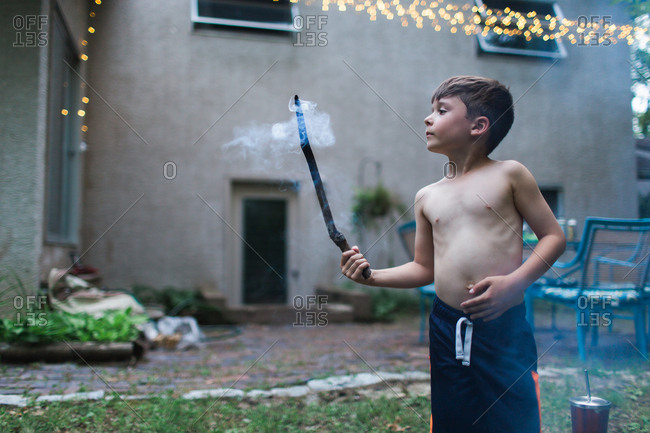 Boy watching smoke curling from burning stick