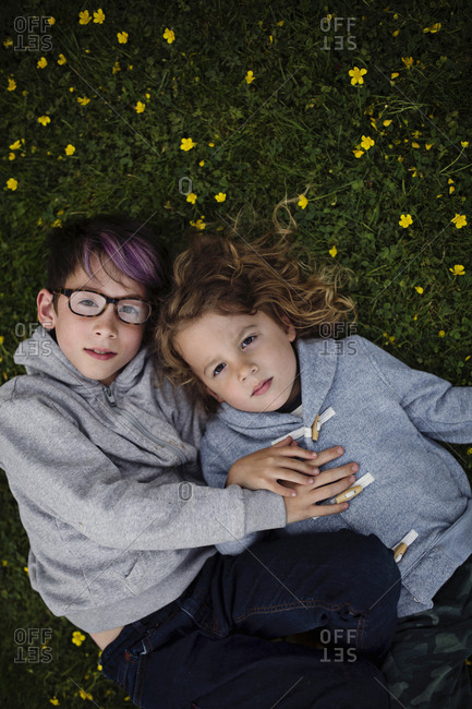 A boy and boy lying in grass together