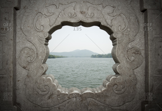 Looking out over the west lake and its shore through a hole on a bridge on the West Lake, the big tourist attraction of  Hangzhou in China