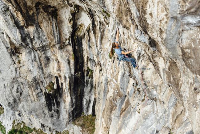 Rock climber woman climbing a steep overhanging limestone a wall, Asturias, Spain