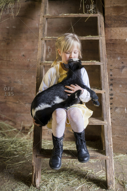 Girl sitting on ladder with goat