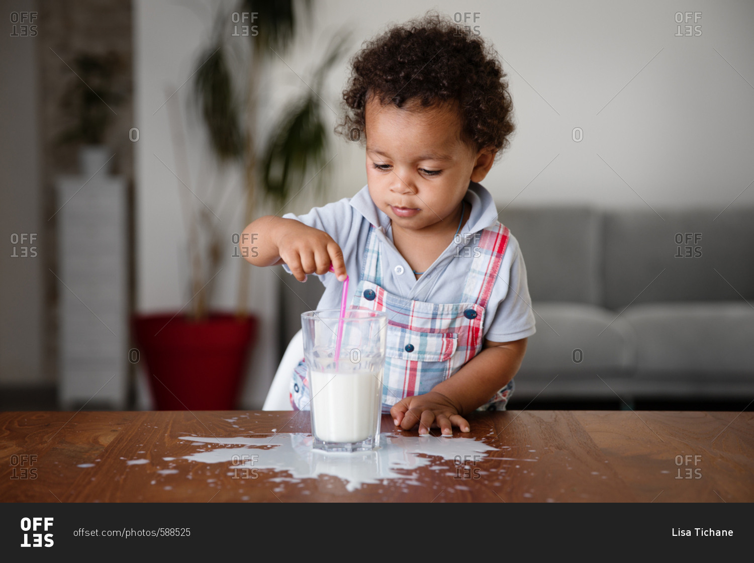 Boy by glass of spilled milk stock photo - OFFSET