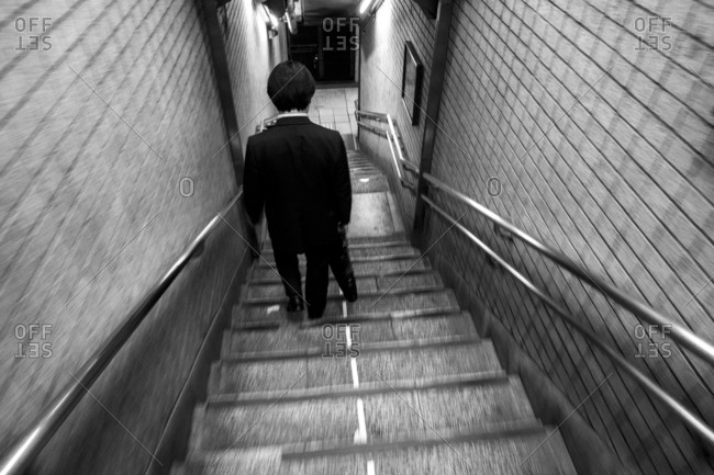 Japanese businessman in a suit walking down staircase at Higashi-Ginza station, Tokyo, Japan