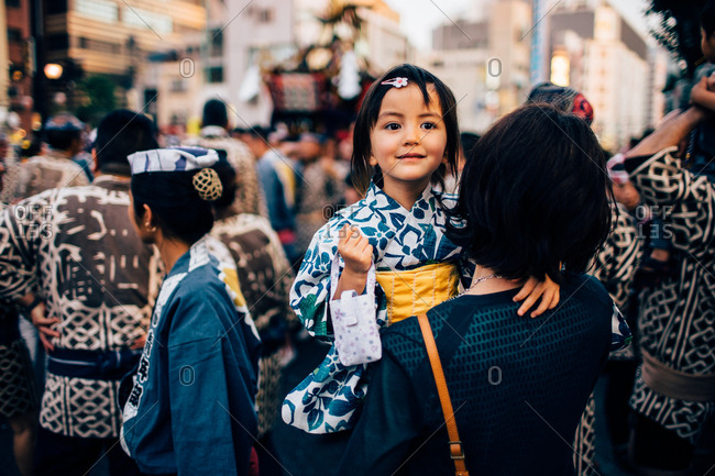 Woman carrying young girl in a crowd of people dressed in traditional costumes