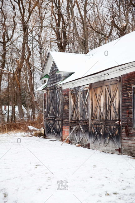Weather-worn barn with many doors in the snow