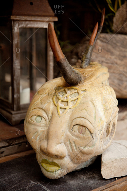Carved sculpture of a persons head with wooden horns on a table