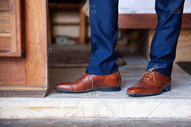 Man in brown leather loafers and blue pants in a doorway