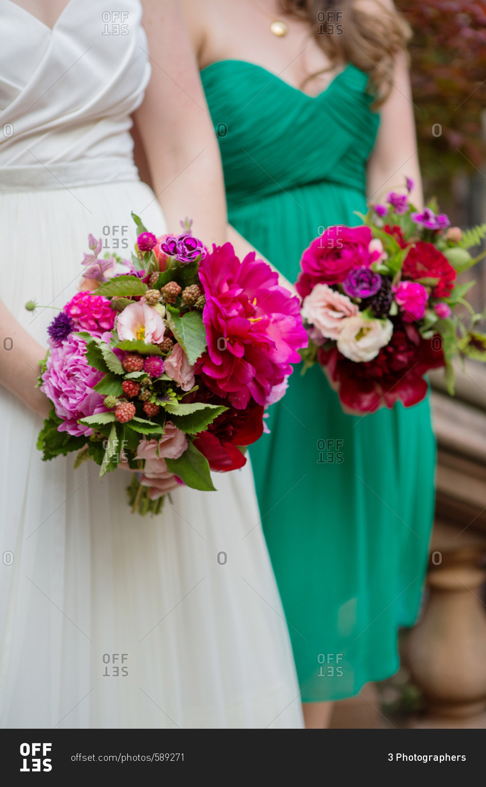 Bride and bridesmaid holding bouquets of pink and purple flowers