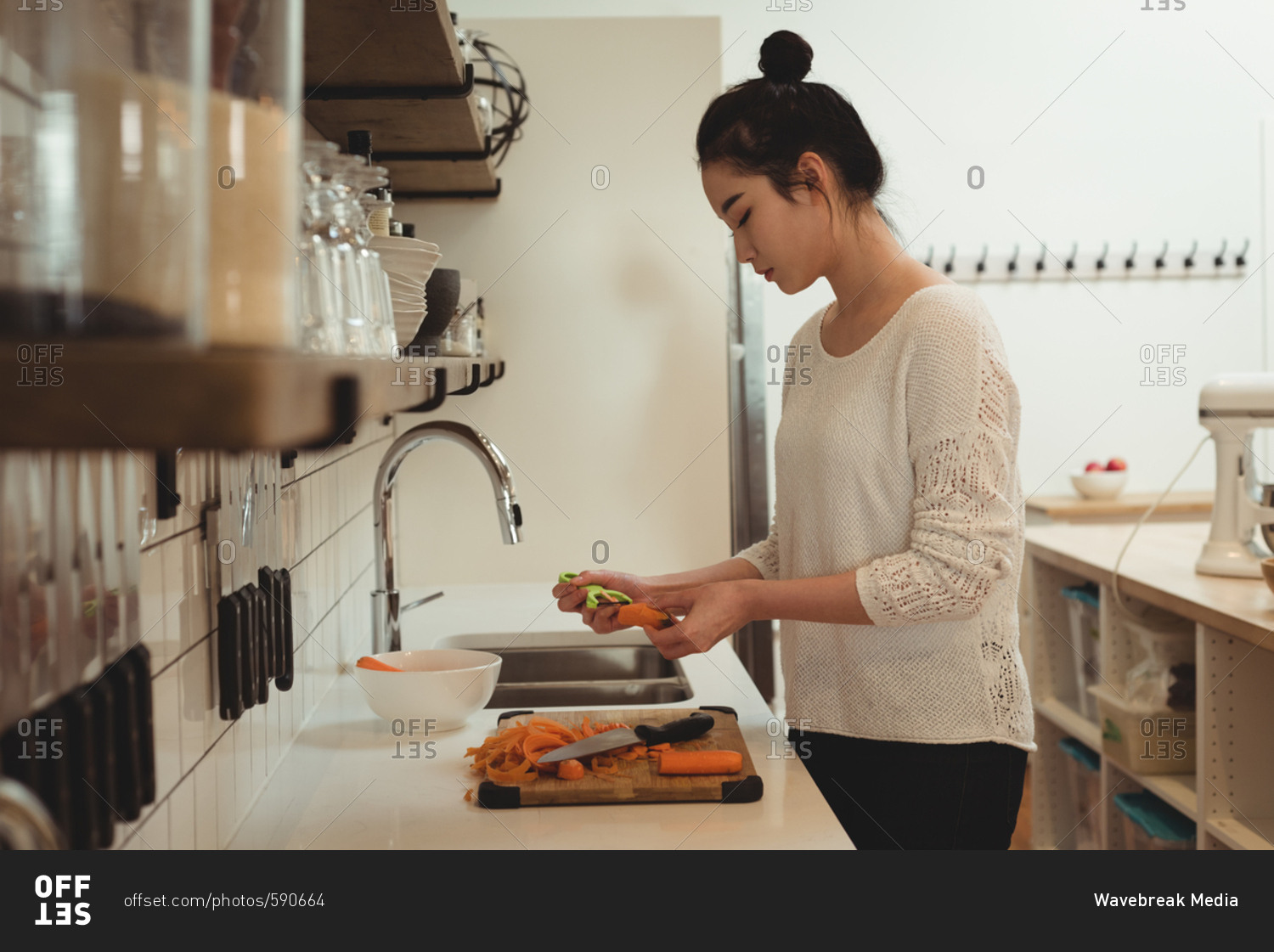 Beautiful woman peeling vegetables in kitchen sink at home
