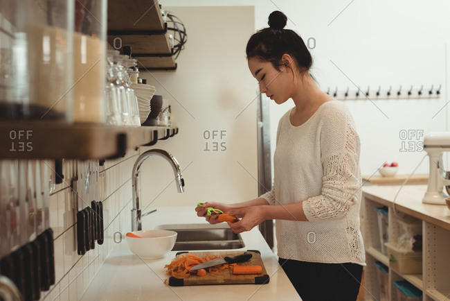 Beautiful woman peeling vegetables in kitchen sink at home