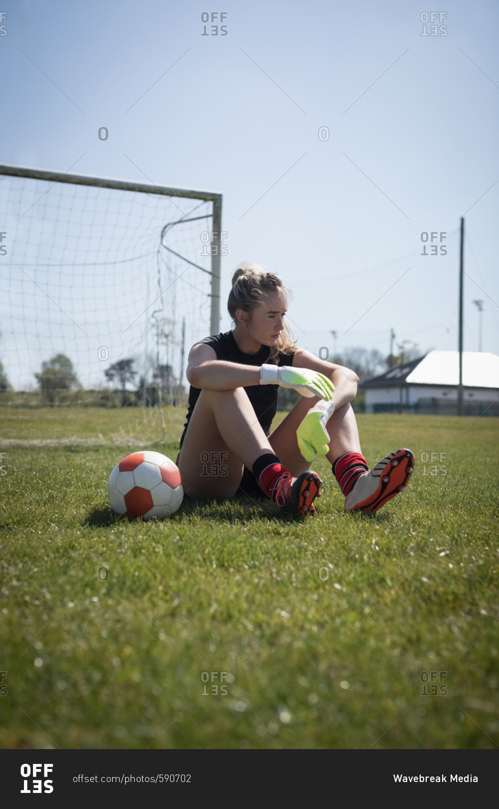 Full length of female soccer player relaxing on playing field