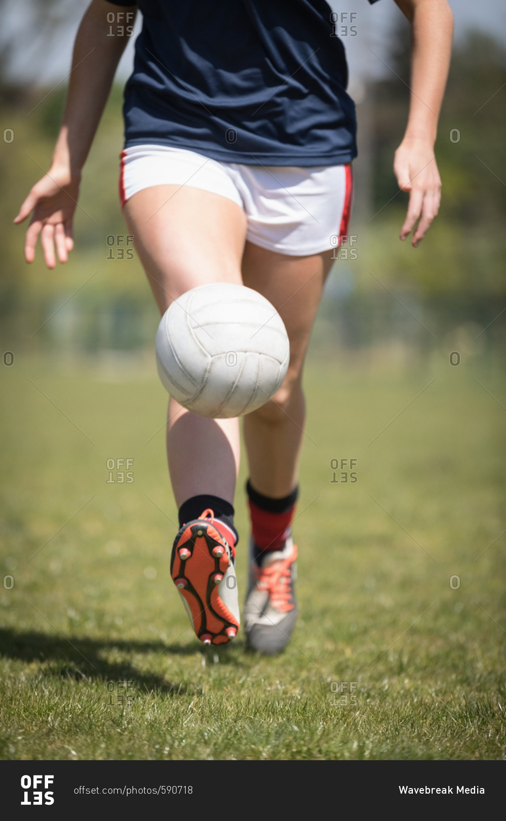 Low section of female player playing with soccer ball on field