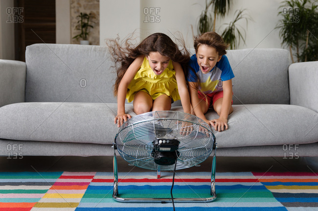 Kids on couch playing with fan