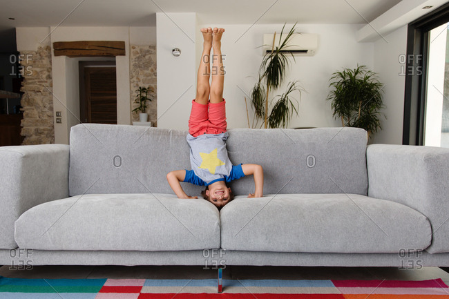 Boy doing headstand on couch