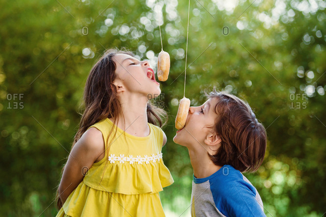Boy and girl eating doughnuts on strings