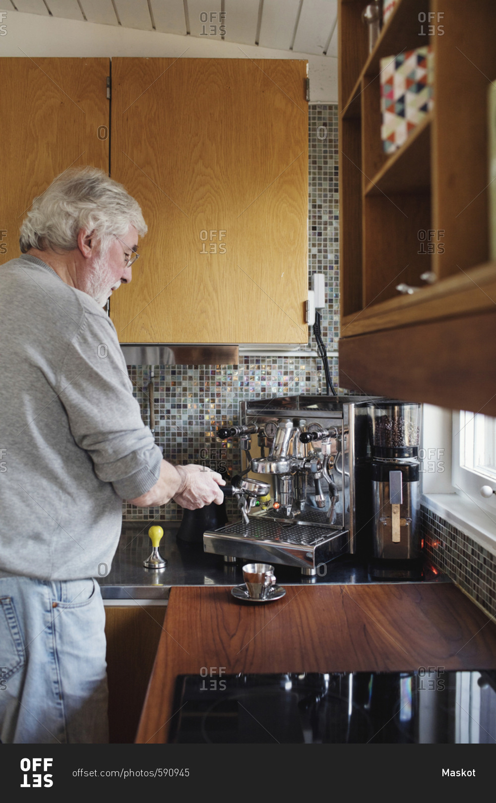 Senior man using coffee maker on kitchen counter at home