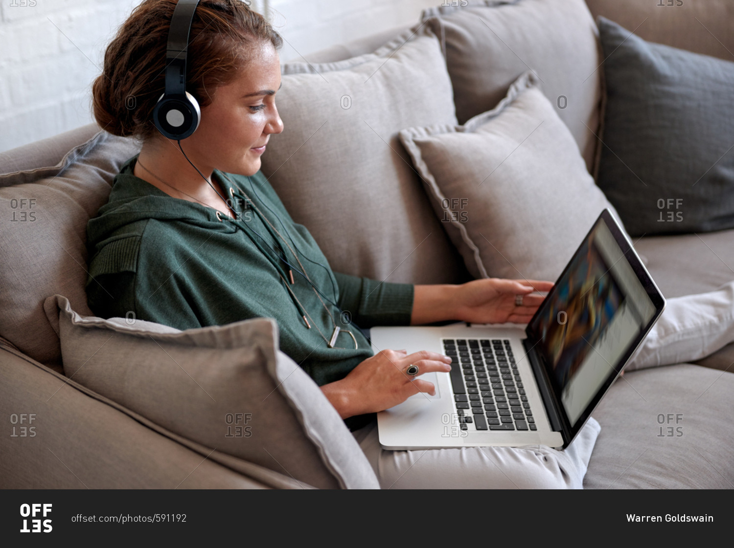 Woman sitting on comfortable couch watching videos on computer