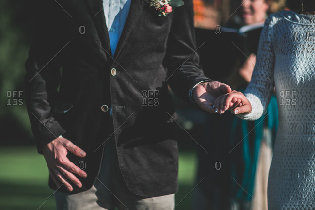 Alternate bridal couple at spiritual wedding ceremony outdoors, detail, hands hold