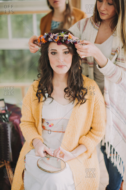 Alternative wedding, preparation, girlfriends decorate bride with floral wreath