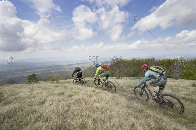 Biker riding bikes through grass on mountain