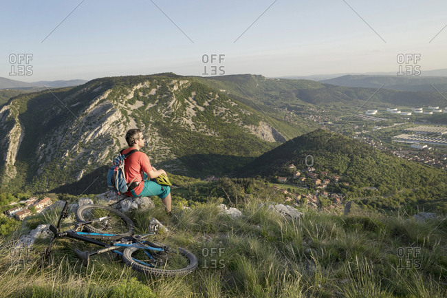 Biker sitting on rock and looking at distance