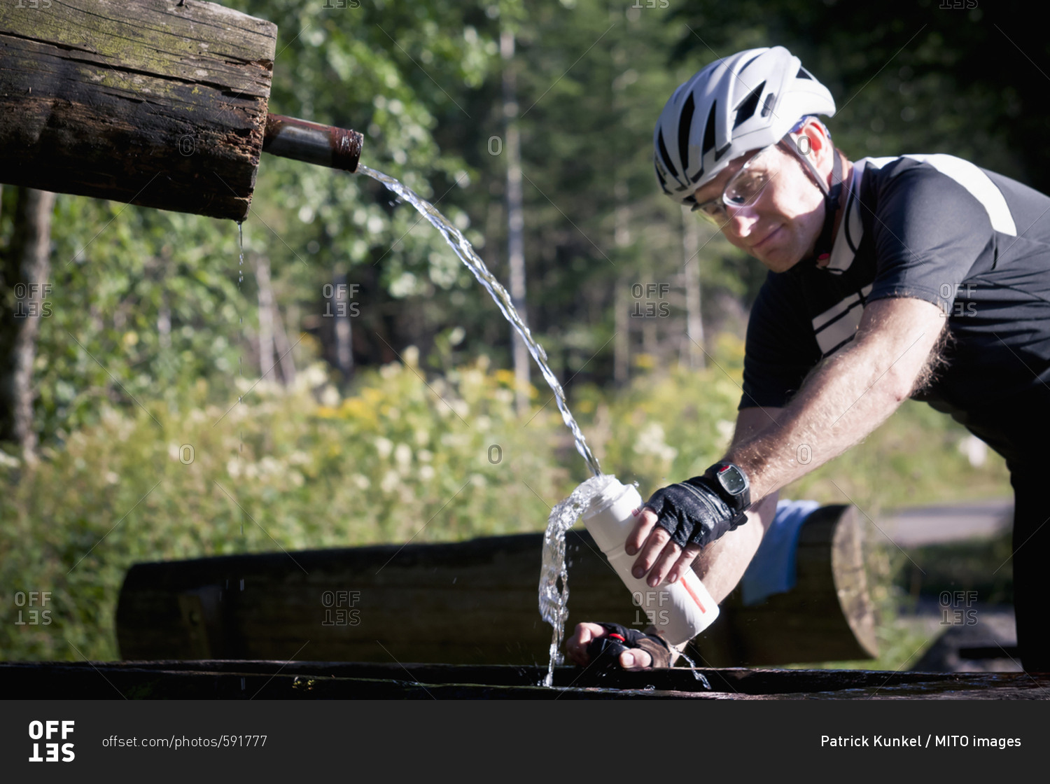 Biker filling water bottle in forest