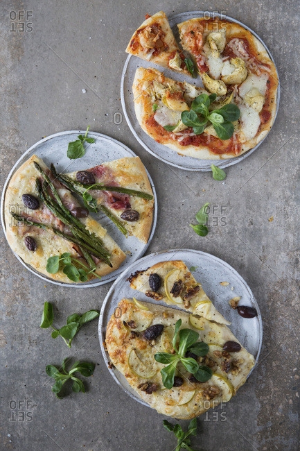 Trio of pizzas, Tomato base, mozzarella, artichoke and lamb lettuce garnish. White base pizza, Parma ham, asparagus, and olives, watercress garnishWhite base pizza, goat cheese, apple, walnuts and olives, lamb lettuce garnish