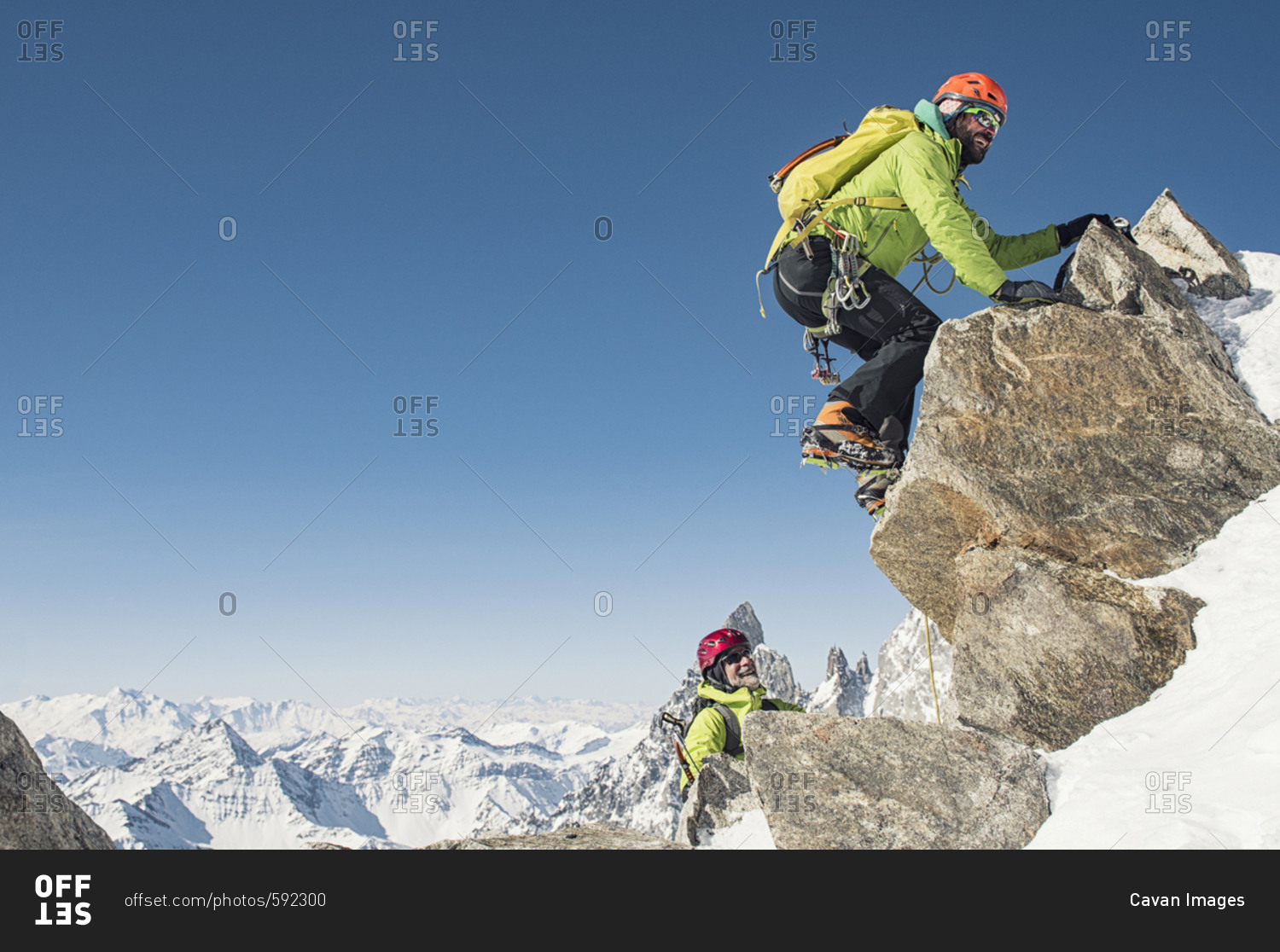 Hikers climbing mountain against clear blue sky during winter on sunny day