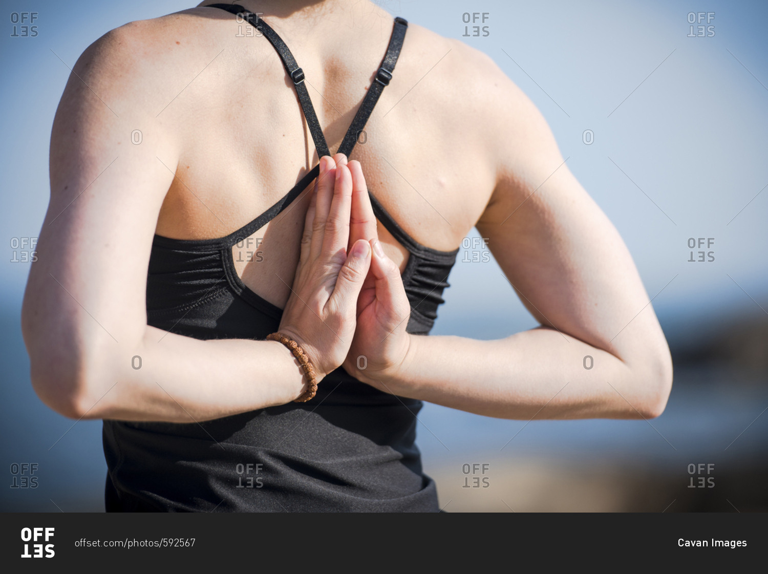 Midsection rear view of woman performing reverse prayer position