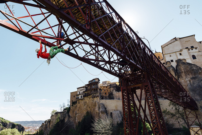 Urban climber hanging from a bridge doing a risk activity in Puente de San Lucas, Cuenca, Spain