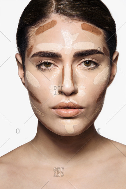 Beautiful young woman with base make up applied on face  for contouring technique to sculpt her features looking at camera