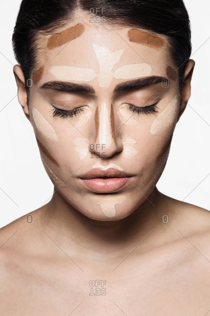 Beautiful young woman with base make up applied on face  for contouring technique to sculpt her features, with eyes closed