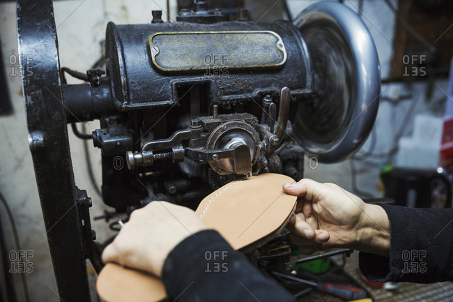 Close up of worker in a shoemaker's workshop, using a machine to sew a leather sole