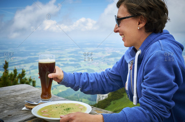Germany- Chiemgau- happy hiker on Hochfelln with glass of beer and dish of pea soup