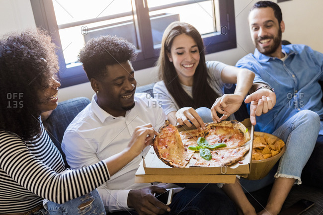 Hy Friends Sitting On The Sofa Sharing A Pizza Stock
