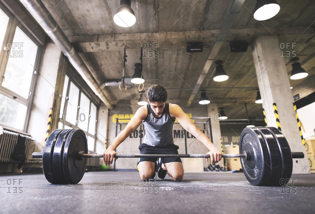 Young athlete exercising with barbell in gym