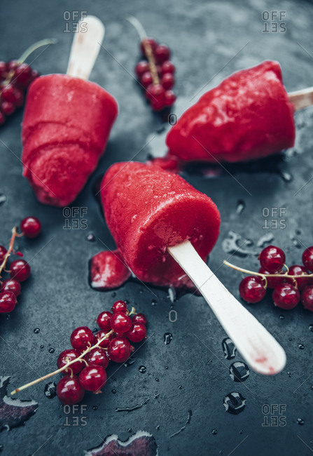 Homemade currant popsicles and red currants on slate