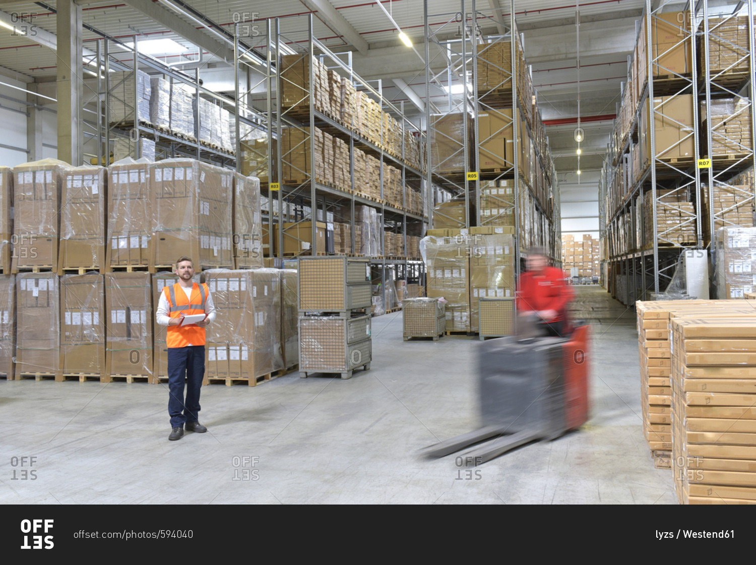 Man in factory hall and moving forklift