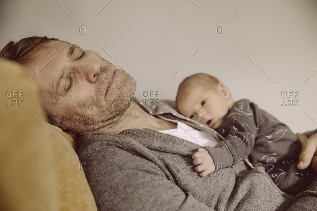 Father taking a nap with newborn awake on his chest