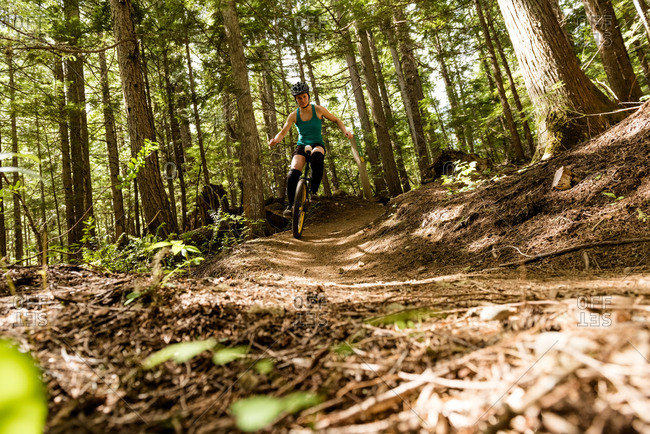 Surface level view of woman unicycling on trial against trees in forest