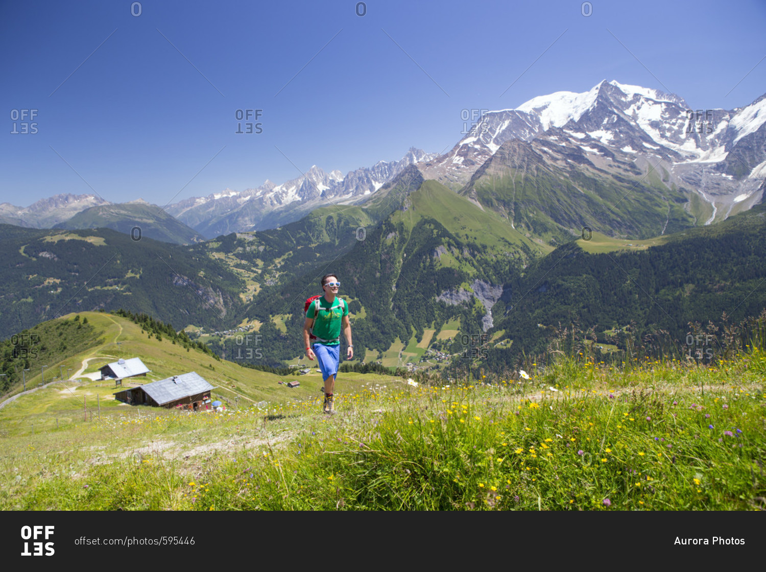 A male hiker is ascending Mont Joly, with Mont Blanc in the background. The peak is part of the Tour du Mont Blanc, a classic multi day trekking around the highest mountain of the Alps.