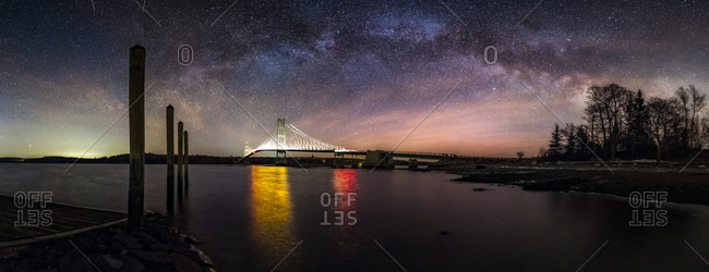 Deer Isle Bridge Milky Way Panorama Maine  The Milky Way arcs over the Deer Isle Bridge on a cold night in February.  The bridge is lit up from the headlamps of trucks.  Nikon D810A, Nikon 14-24mm f/2.8 lens @ 14mm, f/2.8.  10 vertical shots at ISO 10,000