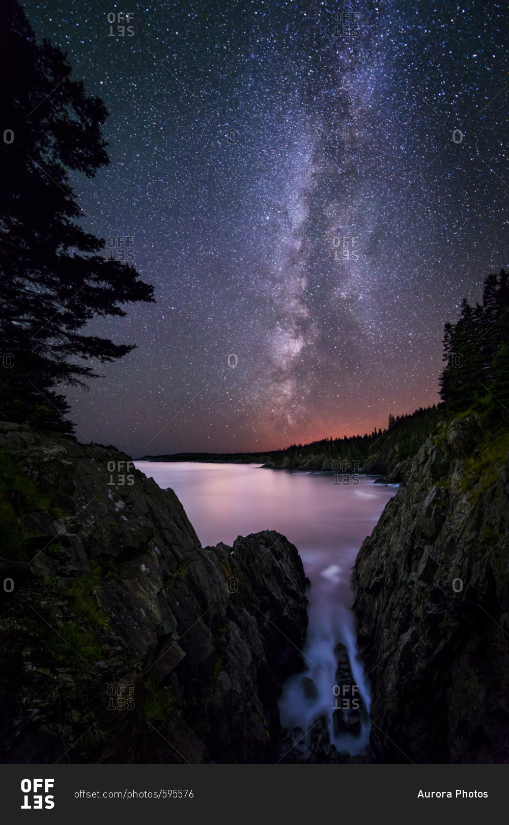 The Milky Way from the dramatic cliffs in Cutler, Maine, with the red glow of the tall antenna tower array at Cutler Naval Base in the background.