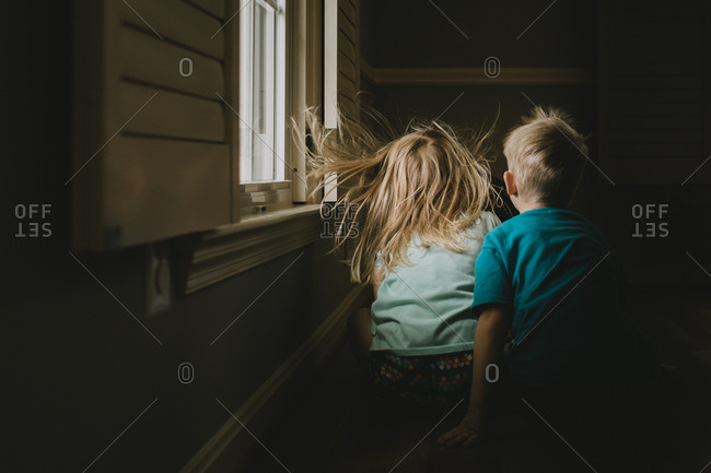 Siblings sitting on outside steps playing in front of fan